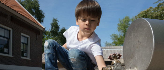 Jongen bij kraan op de waterspeelplaats