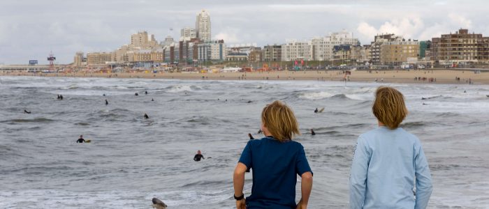 Jongens kijken vanaf de pier naar de surfers