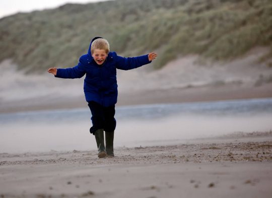 Kind op strand in stevige wind