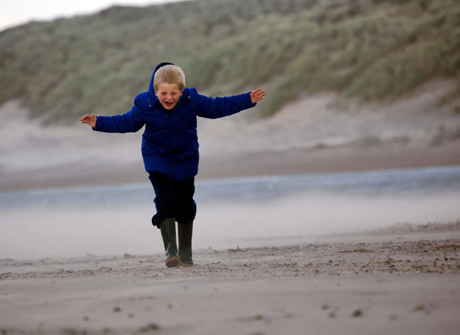 Kind op strand in stevige wind